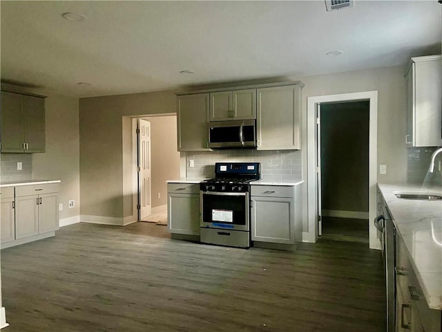 kitchen featuring sink, gray cabinets, appliances with stainless steel finishes, backsplash, and dark hardwood / wood-style floors