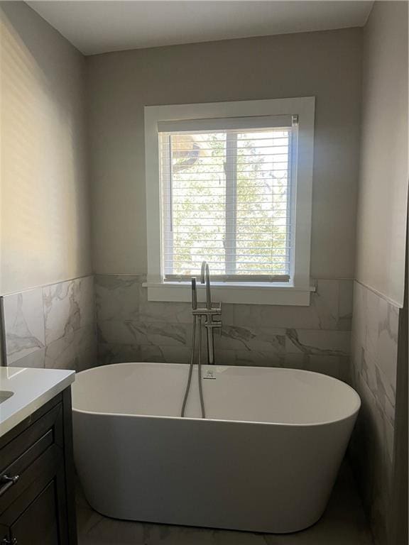 bathroom featuring vanity, tile walls, and a tub