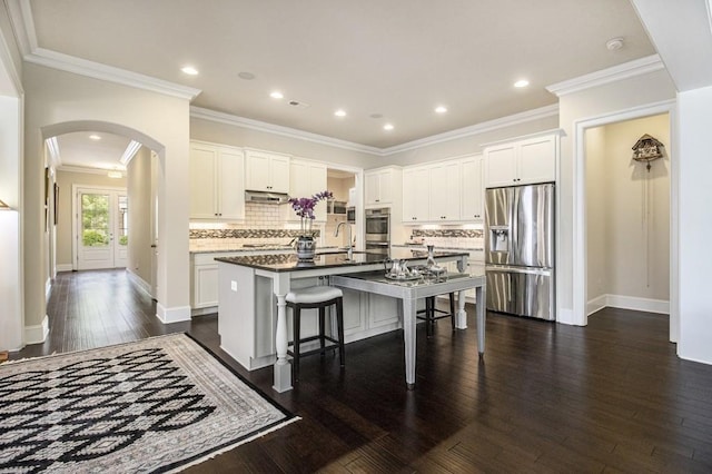 11375 Crestview Ter, Johns Creek, GA 30024 - kitchen featuring appliances with stainless steel finishes, arched walkways, dark wood-type flooring, an island with sink, and a kitchen breakfast bar