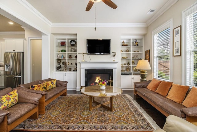 11375 Crestview Ter, Johns Creek, GA 30024 - living area featuring a ceiling fan, ornamental molding, a glass covered fireplace, dark wood-style flooring, and built in features