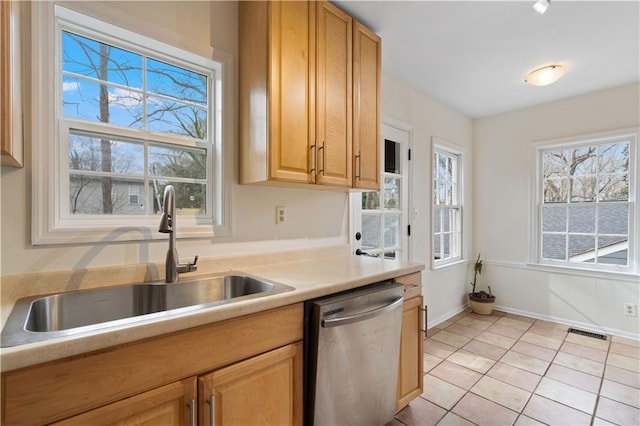 kitchen featuring dishwasher, sink, light tile patterned flooring, and light brown cabinets