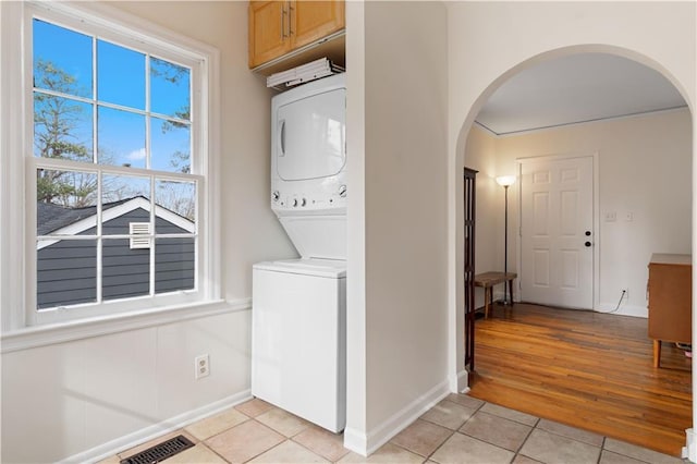 laundry room with stacked washer / drying machine and light tile patterned floors