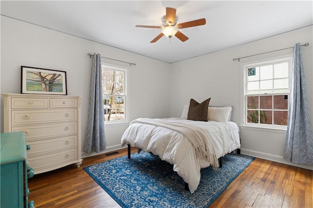 bedroom with multiple windows, dark wood-type flooring, and ceiling fan