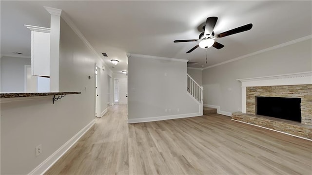 unfurnished living room with a fireplace, crown molding, ceiling fan, and light hardwood / wood-style flooring