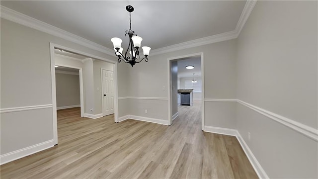 unfurnished dining area with ornamental molding, light wood-type flooring, and an inviting chandelier