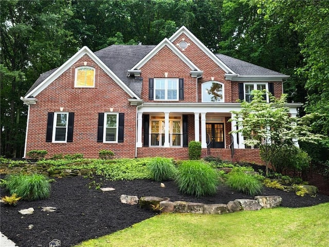 1045 River Pt, Suwanee, GA 30024 - view of front of home with brick siding, a front lawn, and a porch