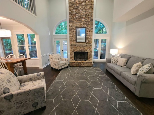 1045 River Pt, Suwanee, GA 30024 - living area with dark wood-type flooring, a high ceiling, a fireplace, arched walkways, and french doors