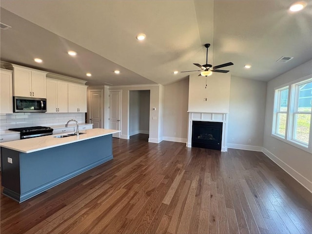 kitchen featuring white cabinetry, sink, black electric range oven, and a center island with sink