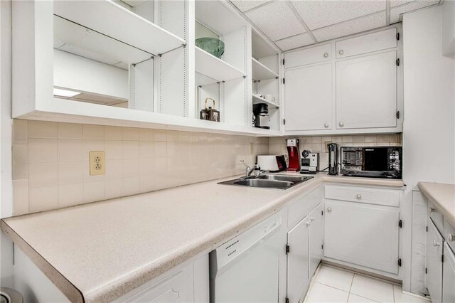 kitchen featuring decorative backsplash, light tile patterned flooring, white cabinetry, dishwasher, and a drop ceiling