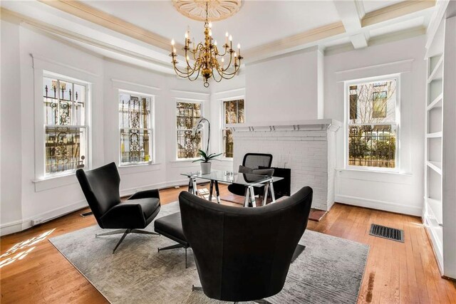 sitting room with light wood-type flooring, a fireplace, a notable chandelier, and plenty of natural light