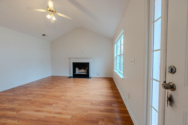 unfurnished living room with a fireplace with flush hearth, lofted ceiling, light wood-style flooring, baseboards, and ceiling fan