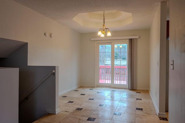 doorway with a notable chandelier, a textured ceiling, a raised ceiling, and baseboards