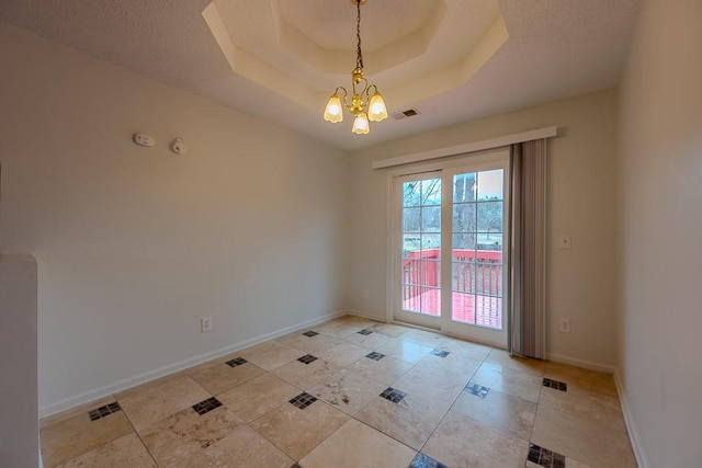 spare room with baseboards, a raised ceiling, visible vents, and a chandelier