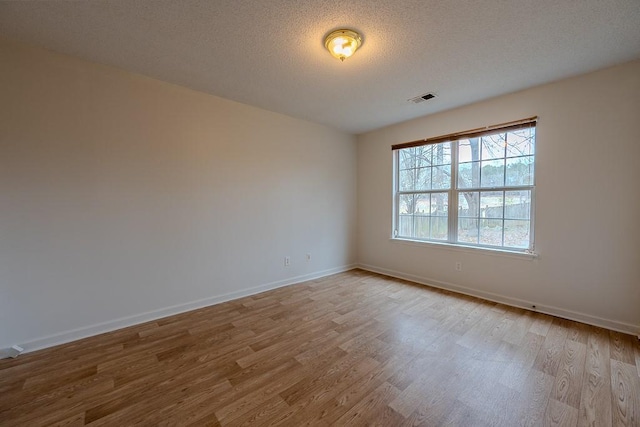 unfurnished room featuring visible vents, a textured ceiling, and wood finished floors