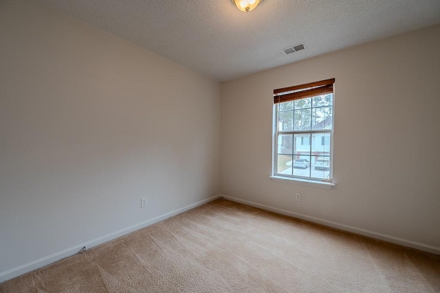 empty room featuring visible vents, baseboards, light colored carpet, and a textured ceiling