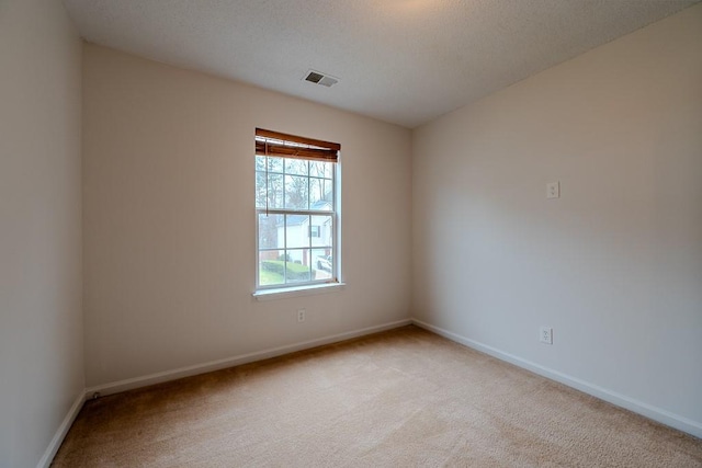 empty room with visible vents, baseboards, light colored carpet, and a textured ceiling