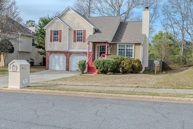 split level home featuring a chimney, concrete driveway, a front lawn, a garage, and brick siding