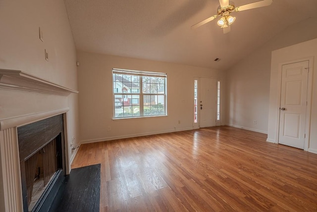 unfurnished living room featuring lofted ceiling, a fireplace with flush hearth, wood finished floors, and baseboards