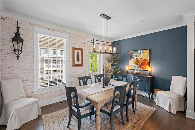 dining space featuring an inviting chandelier, baseboards, ornamental molding, and dark wood finished floors