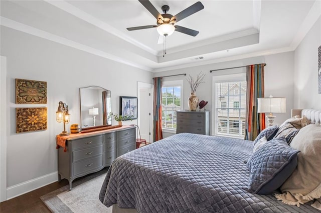 bedroom featuring visible vents, ornamental molding, wood finished floors, baseboards, and a tray ceiling