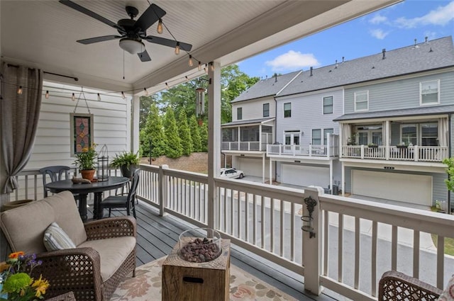 deck featuring an attached garage and a ceiling fan