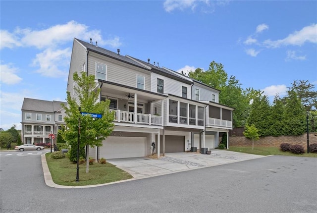 back of house with ceiling fan, driveway, a sunroom, a garage, and a balcony