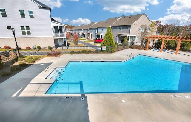 community pool with a patio, fence, a pergola, and a residential view