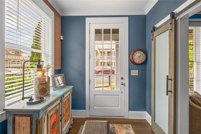 doorway with baseboards, ornamental molding, dark wood-style floors, and a barn door