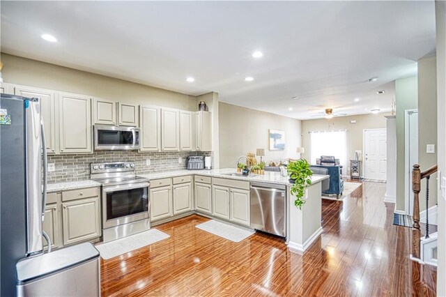 3068 Cedar Glade Ln, Buford, GA 30519 - kitchen with sink, kitchen peninsula, stainless steel appliances, light hardwood / wood-style floors, and backsplash
