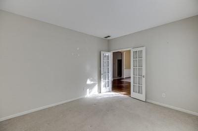 empty room with french doors and light colored carpet