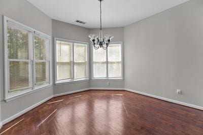 unfurnished dining area featuring a notable chandelier and dark hardwood / wood-style floors