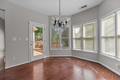 unfurnished dining area featuring a chandelier, dark wood-type flooring, and a wealth of natural light