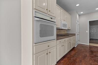 kitchen featuring dark wood-type flooring, white appliances, and white cabinetry