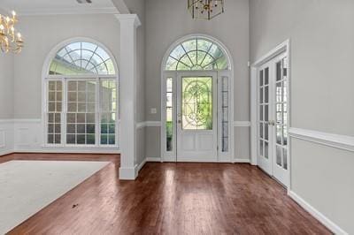 foyer entrance featuring dark wood-type flooring, french doors, crown molding, and an inviting chandelier