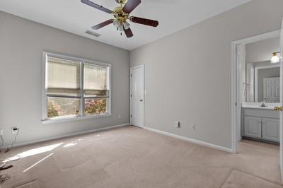 unfurnished bedroom featuring light carpet, ensuite bathroom, and ceiling fan