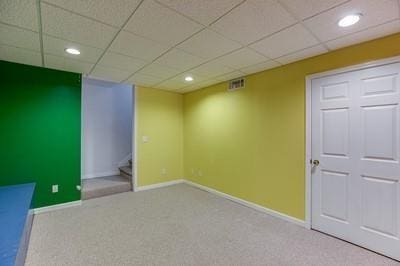 basement featuring a drop ceiling and carpet floors