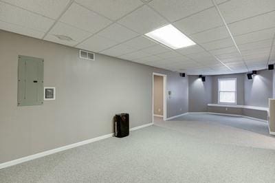 basement featuring a drop ceiling, electric panel, and carpet floors