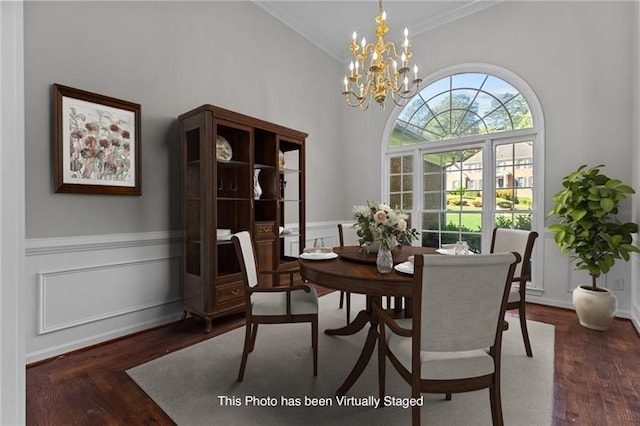 dining area with a towering ceiling, a notable chandelier, dark hardwood / wood-style floors, and ornamental molding