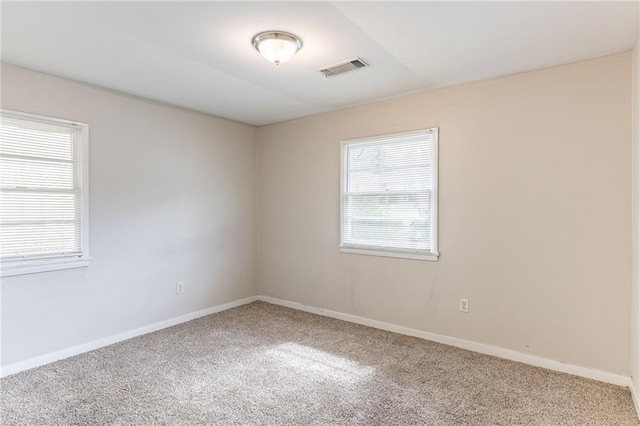 carpeted spare room featuring visible vents and baseboards