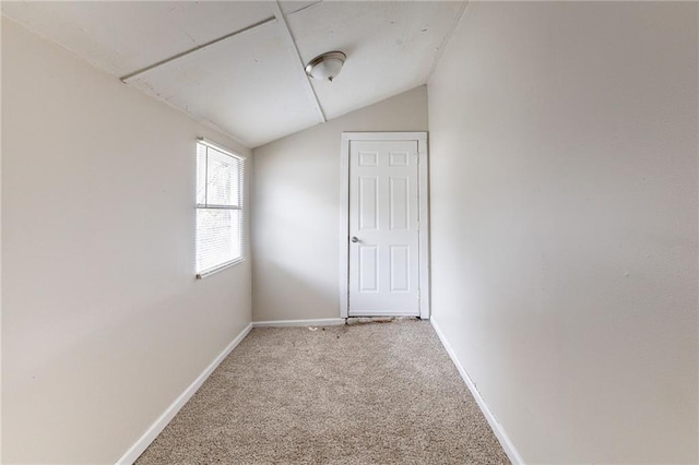 empty room featuring vaulted ceiling, carpet, and baseboards