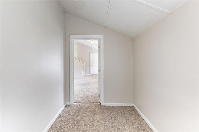 empty room with lofted ceiling, baseboards, and light colored carpet