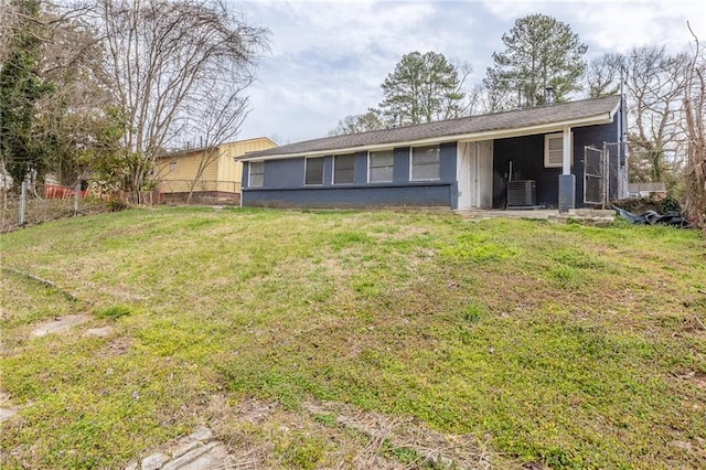 back of property with central air condition unit, fence, and a lawn