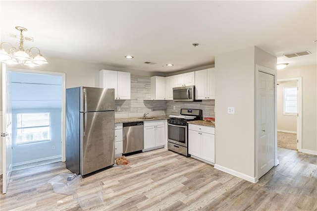 kitchen featuring visible vents, decorative backsplash, appliances with stainless steel finishes, white cabinetry, and light wood-type flooring