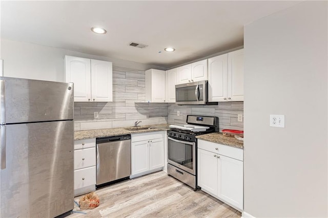 kitchen with white cabinetry, appliances with stainless steel finishes, backsplash, and a sink