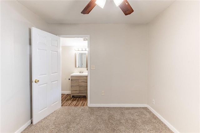 unfurnished bedroom with carpet floors, ensuite bathroom, a sink, ceiling fan, and baseboards