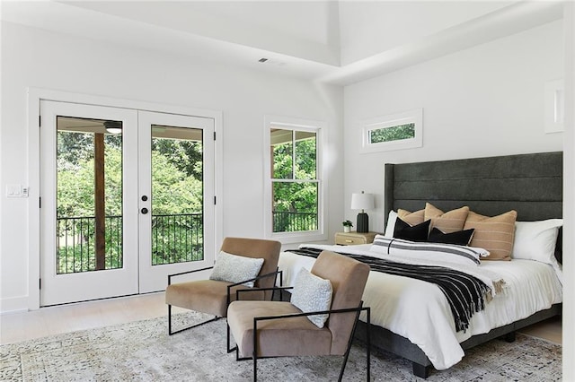 bedroom featuring a high ceiling, wood-type flooring, access to outside, and french doors