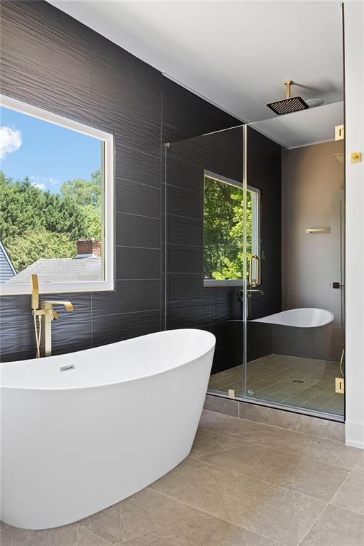 bathroom featuring a shower with shower door, tile walls, and tile patterned floors