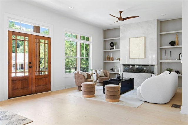 interior space with ceiling fan, french doors, built in shelves, and hardwood / wood-style flooring