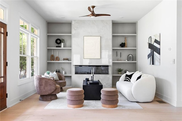 sitting room with light hardwood / wood-style floors, built in features, and ceiling fan