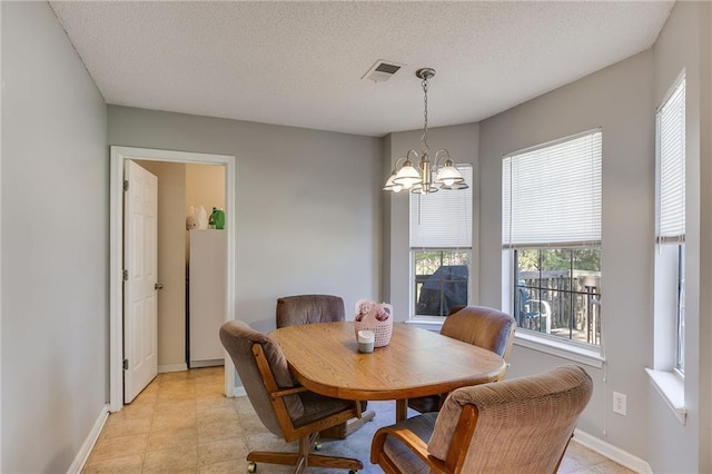 dining room with visible vents, a notable chandelier, a textured ceiling, and baseboards